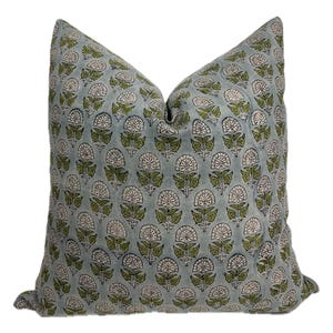 May include: Square throw pillow with a repeating floral pattern in white and green on a light blue background. The pillow is a soft square shape, perfect for adding a decorative touch to any room.