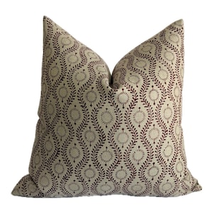 May include: A decorative throw pillow with a beige background and a repeating pattern of dark red floral and leaf-like shapes. The pillow is rectangular and has a soft, inviting appearance, suitable for home decor.