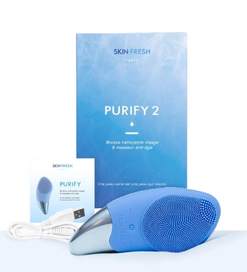 May include: A blue facial cleansing brush with a silver handle and a USB charging cable. The product is labeled "PURIFY 2" and "SKIN FRESH PARIS". The packaging includes a box and a smaller card with the product name and logo.