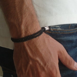 May include: A black braided bracelet with a silver clasp.