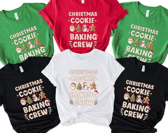 May include: A collection of short-sleeved t-shirts in various colors, including green, red, black, and white. Each shirt features the text "CHRISTMAS COOKIE BAKING CREW" with festive graphics of Santa, a Christmas tree, and gingerbread men.