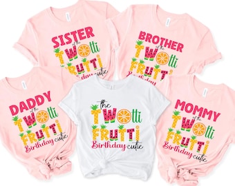 May include: Five short-sleeved t-shirts. Four are light pink, and one is white. Each shirt has a colorful graphic with the words "Sister," "Brother," "Daddy," and "Mommy" or "The" with the words "TWOtti FRUTTI Birthday cutie."