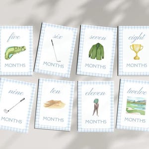 May include: Set of 10 blue and white gingham cards with golf-themed illustrations and the numbers five through twelve with the word "MONTHS" below each number.