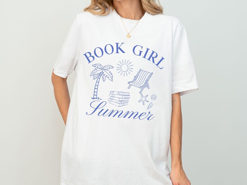 May include: White t-shirt with a blue graphic that reads "Book Girl Summer." The design includes a palm tree, sun, beach chair, books, and starfish. A casual, comfortable tee for book lovers.