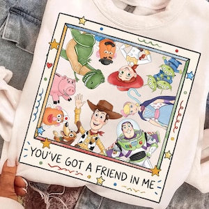 Puede incluir: Sudadera blanca con un gr&aacute;fico colorido de personajes de Toy Story. El dise&ntilde;o est&aacute; enmarcado con estrellas y el texto "YOU'VE GOT A FRIEND IN ME".