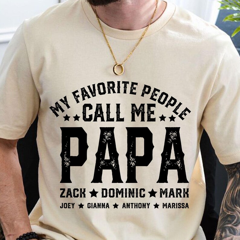 May include: A beige t-shirt with black text that reads "My favourite people call me Papa" with a list of names below: Zack, Dominic, Mark, Joey, Gianna, Anthony, Marissa.