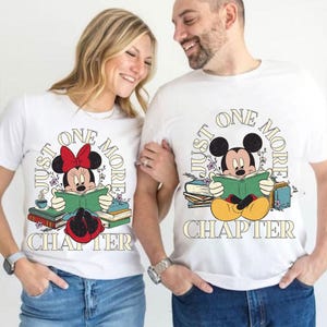Op de afbeelding: Een stel draagt witte T-shirts met een Mickey Mouse en Minnie Mouse ontwerp. De shirts zeggen "Just One More Chapter" met een stapel boeken en bloemen.