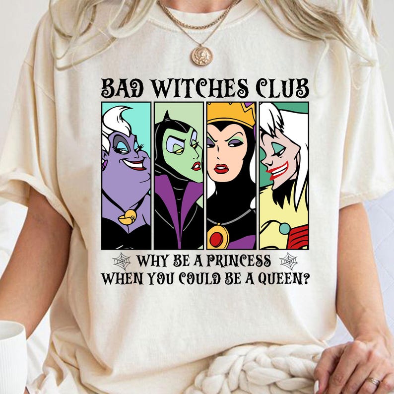 Puede incluir: Una camiseta blanca con un estampado gr&aacute;fico de cuatro villanas de Disney: &Uacute;rsula, Mal&eacute;fica, la Reina Malvada y Cruella de Vil. El texto dice "Bad Witches Club" y "Why be a princess when you could be a queen?"