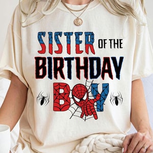 May include: White t-shirt with the text "Sister of the Birthday Boy" in black. A red and blue Spiderman character is in the center of the shirt with a web design.