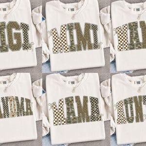 May include: Six off-white crewneck sweatshirts featuring block-letter graphics that spell GIGI, MIMI, NANA, GRANDMA, MAMA, and AUNTIE. Each letter displays a mix of checkered, camouflage, leopard print, and polka dot patterns with small bow accents.