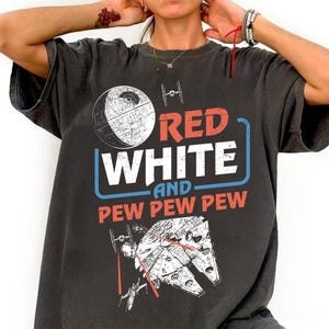 May include: A black t-shirt with a graphic design featuring a Star Wars themed image. The text on the shirt reads "Red White and Pew Pew Pew".