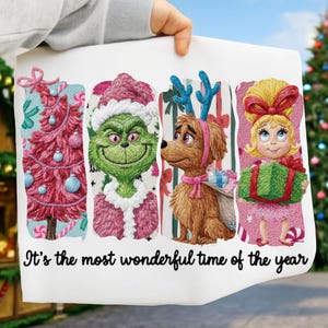May include: A white Christmas-themed print featuring embroidered images of a pink Christmas tree, the Grinch, a dog with antlers, and a girl holding a gift. The text "It's the most wonderful time of the year" is at the bottom.