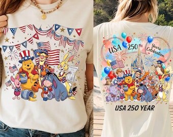 Può includere: T-shirt color crema con un design patriottico con personaggi dei cartoni animati. La parte anteriore mostra Winnie the Pooh, Tigro, Eeyore, Pimpi e Coniglio con bandiere americane e fuochi d'artificio. Il retro dice "USA 250 Years Celebration".
