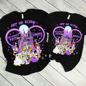 May include: Black t-shirts with a Halloween design. The shirts feature a purple and white graphic with the text "NOT SO SCARY" and "HALLOWEEN PATTY" and "DANIEL" on one shirt and "ANGELA" on the other. The design includes cartoon characters.