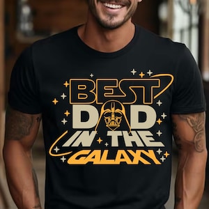 May include: Black t-shirt with a yellow graphic that says "Best Dad in the Galaxy" with a Darth Vader silhouette in the middle of the text.