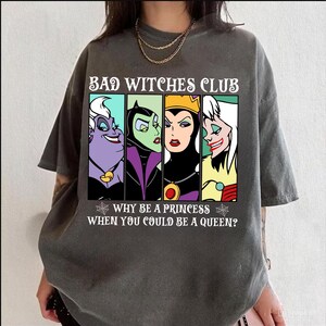 Puede incluir: Una camiseta gris oscuro con un estampado gr&aacute;fico de cuatro personajes villanos de Disney: &Uacute;rsula, Mal&eacute;fica, la Reina Malvada y Cruella de Vil. El texto "Bad Witches Club" est&aacute; por encima de los personajes y el texto "Why be a princess when you could be a queen?" est&aacute; por debajo de los personajes.