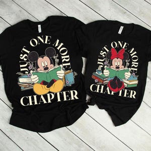 Op de afbeelding: Twee zwarte T-shirts met een afbeelding van Mickey en Minnie Mouse die boeken lezen. De tekst op de shirts luidt "Just One More Chapter".