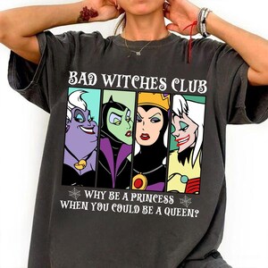 Puede incluir: Una camiseta negra con un gr&aacute;fico de estilo vintage que presenta cuatro personajes de villanos de Disney: &Uacute;rsula, Mal&eacute;fica, la Reina Malvada y Cruella de Vil. El texto dice "Bad Witches Club" y "&iquest;Por qu&eacute; ser una princesa cuando puedes ser una reina?"