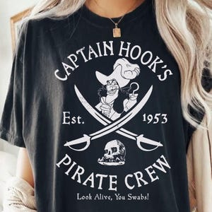 May include: Black t-shirt with a white graphic of Captain Hook, crossed swords, and a skull. Text reads "CAPTAIN HOOK'S PIRATE CREW Est. 1953" and "Look Alive, You Swabs!" is printed at the bottom.