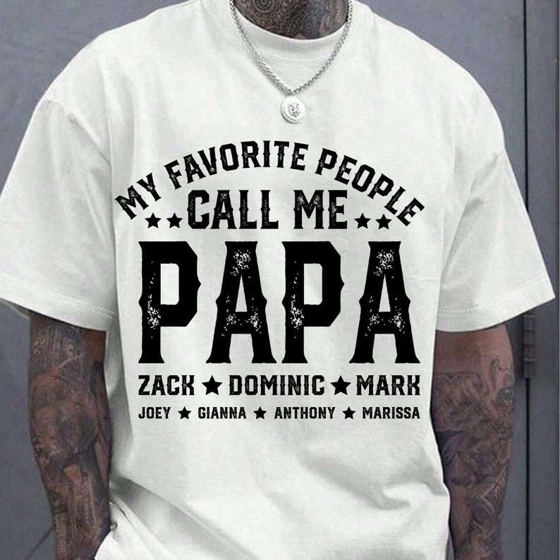 May include: White t-shirt with black text that reads "My Favourite People Call Me Papa" with names listed below.