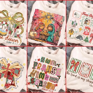 May include: White sweatshirts with Christmas-themed designs. One features "LOVE came down" with a nativity scene. Another displays a nativity scene with Mary, Joseph, and baby Jesus. Other designs include "I will praise Him in every season" and "The Lord is my shepherd."