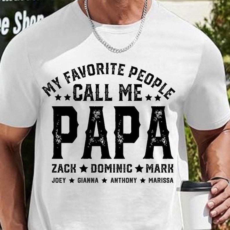 May include: White t-shirt with black text that reads "My Favourite People Call Me Papa" with the names Zack, Dominic, Mark, Joey, Gianna, Anthony, and Marissa listed below.