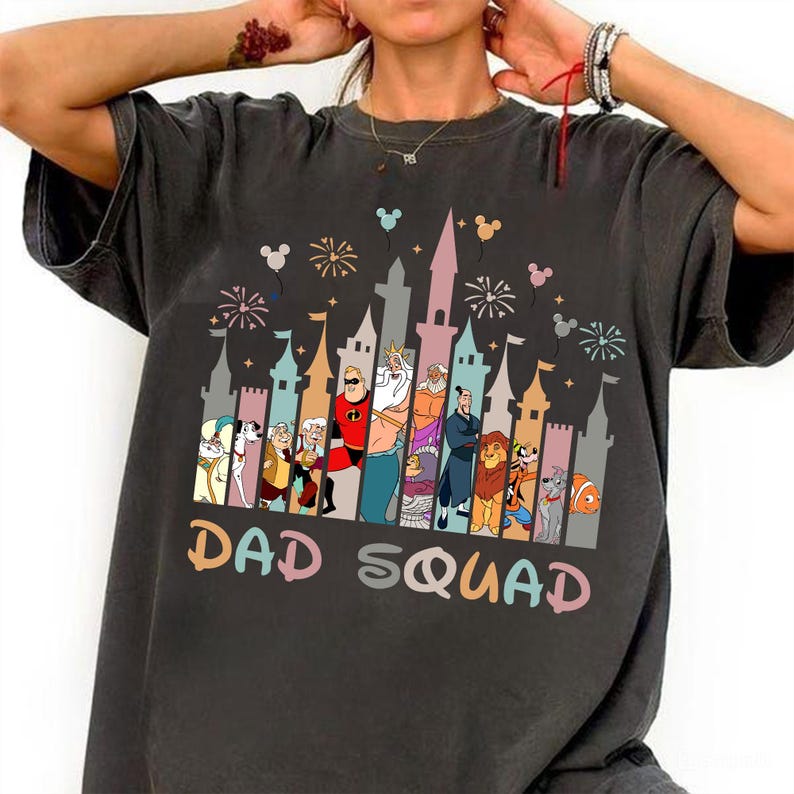 May include: A dark gray t-shirt with a graphic of a Disney castle and characters. The text "DAD SQUAD" is printed below the graphic.