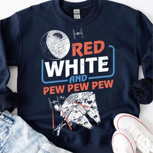 May include: Navy blue sweatshirt with a white and red graphic design. The graphic features a Death Star, a starfighter, and the text "Red White and Pew Pew Pew".