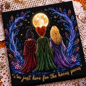 May include: A black fabric square featuring a graphic illustration of three figures in hooded cloaks of red, green, and purple standing before a full moon. The design includes blue trees and the text "i'm just here for the hocus pocus" in gold.
