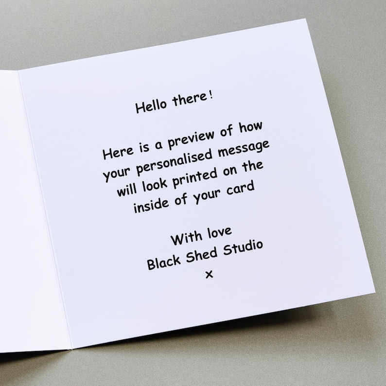 Peut inclure: Une carte de v&oelig;ux blanche ouverte avec du texte noir. Le texte se lit comme suit : "Bonjour ! Voici un aper&ccedil;u de l'apparence de votre message personnalis&eacute; &agrave; l'int&eacute;rieur de votre carte. Avec amour Black Shed Studio x."