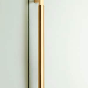 Puede incluir: Un tirador de puerta de color dorado. El tirador es cilíndrico con extremos cuadrados, montado sobre una superficie blanca. El tirador mide aproximadamente 30 cm de largo.