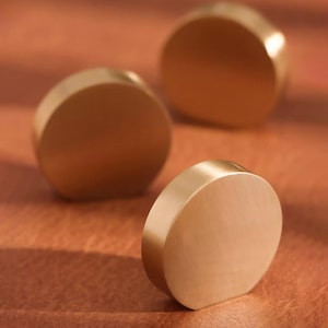 Pu&ograve; includere: Tre pomelli rotondi per armadio in ottone massiccio. I pomelli sono lisci e hanno una finitura lucida.