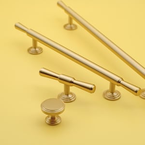以下が含まれることがあります： 4つの異なるスタイルとサイズの金色のキャビネットハードウェアプル。プルには、丸いノブ、T字型のプル、2つの長いバープルが含まれています。