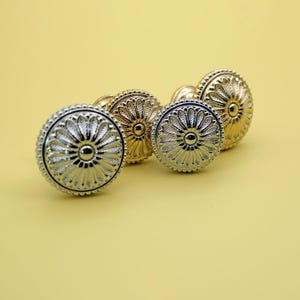 May include: Three decorative cabinet knobs with a floral design. The knobs are in silver and gold finishes.