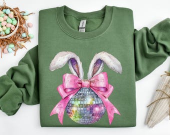 Può includere: Felpa verde con un uovo di Pasqua a forma di discoteca scintillante con orecchie di coniglio rosa e un fiocco rosa.