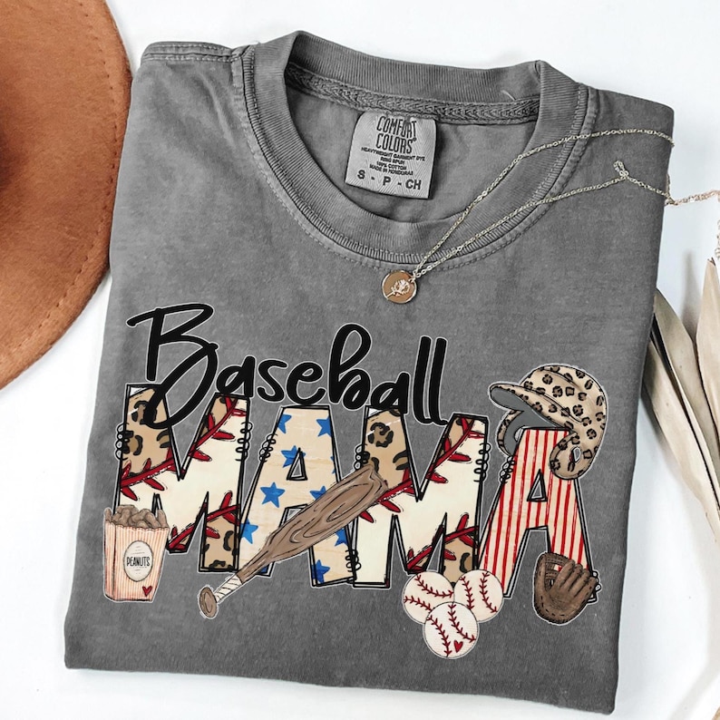 May include: Gray Comfort Colors t-shirt with the words "Baseball MAMA" in a baseball-themed design. The design includes a baseball bat, peanuts, baseballs, a baseball glove, and a leopard print baseball helmet.