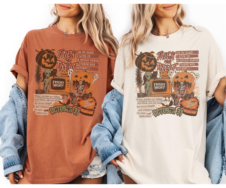May include: Two t-shirts, one rust-colored and one cream-colored, feature a Halloween-themed graphic. The design includes a jack-o'-lantern, alien, and the text "Trick or Treat" and "Fright Night". The text "October 31" is also present.