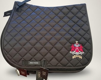 May include: A dark brown quilted saddle pad with a diamond pattern. Features a decorative crest with red and white accents and the text "Bello Reune". Includes black straps and tags.