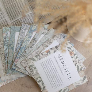 May include: A stack of cards with floral patterns in shades of blue and brown. The top card has the word "MERCIful" printed in black text and a quote about the Lord's mercy.