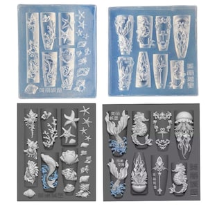 Pode incluir: Dois conjuntos de moldes de silicone para nail art com uma sereia, um cavalo-marinho, uma estrela do mar, conchas e outros desenhos com tema oceânico. Os moldes são cinzentos e azuis.