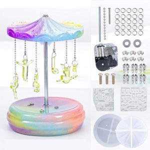 May include: A DIY music box kit featuring a carousel design. The carousel has a rainbow-hued base and canopy, with clear acrylic figures suspended from chains. The kit includes a music box mechanism, hardware, and molds for construction.