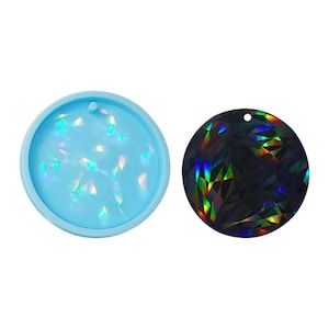 Op de afbeelding: Een ronde siliconen mal en een afgewerkt harsstuk met een holografische, iriserende afwerking. De mal is lichtblauw en het harsstuk is zwart met een regenboogkleurige glans.