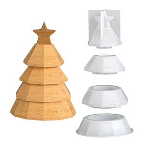 Könnte beinhalten: Ein holzfarbener, weihnachtsbaumförmiger ewiger Kalender mit einem Stern oben. Der Kalender ist hellbraun mit eingravierten Zahlen und Monaten. Daneben befinden sich weiße, baumförmige Formen.