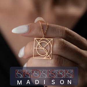 Peut inclure: Un collier pendentif doré avec un design géométrique dans un cadre carré. Le collier est tenu par une main avec du vernis à ongles blanc. Le mot "MADISON" est affiché en bas de l'image.