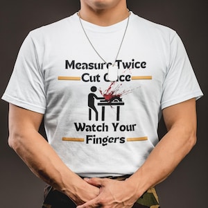 May include: A white t-shirt with the text "Measure Twice Cut Once" and a graphic of a hand being cut by a saw. The text "Watch Your Fingers" is also on the shirt.