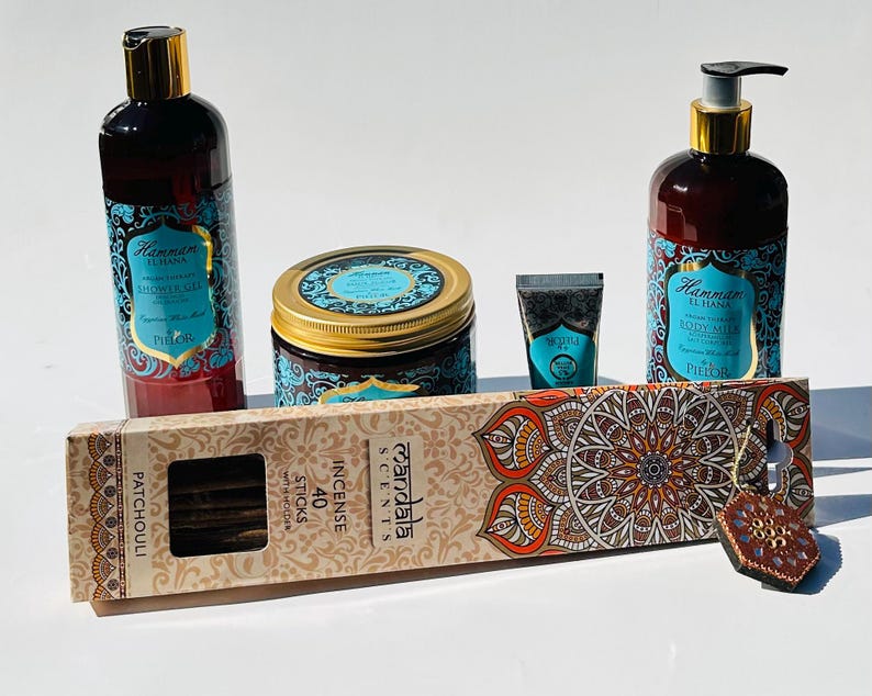 May include: A gift set featuring a blue and gold themed body care products with a Hammam El Hana label. The set includes a body wash, body lotion, body scrub, hand cream, and incense sticks. The incense sticks are labeled "Patchouli" and "40 Sticks".