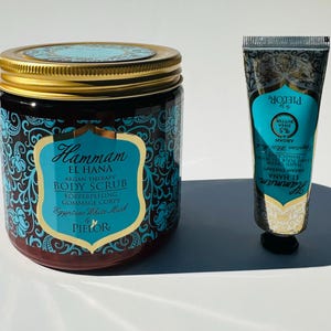 May include: A set of two bath products in a blue and gold design. The larger jar is a body scrub with the text "Hammam El Hana Argan Therapy Body Scrub Korperpeeling Gommage Corps Egyptian White Mask Pielor". The smaller tube is a hand cream with the text "Hammam El Hana Argan Therapy Hand & Nail Cream Moisturizing Pielor".