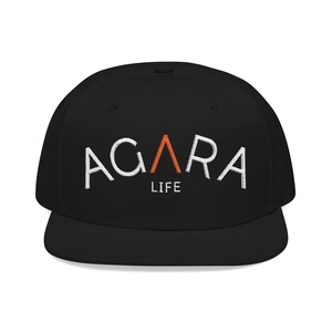 Peut inclure: Casquette de baseball noire à visière plate. Le texte blanc brodé "AGARA" est présent, avec un triangle orange et le mot "LIFE" en dessous. Un accessoire classique et décontracté.