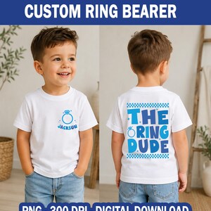 Puede incluir: Camiseta blanca con un gráfico de anillo azul y el nombre "Jackson" impreso en la parte delantera. La parte trasera de la camiseta presenta el texto "THE RING DUDE" en azul. La camiseta está diseñada para un portador de anillos.