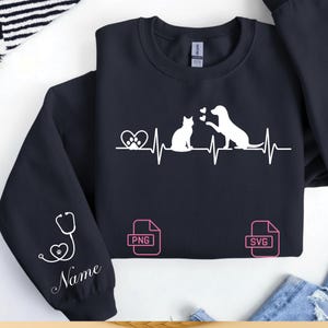 Może przedstawiać: Granatowa bluza z białym nadrukiem kota i psa z linią bicia serca. Projekt zawiera odcisk łapy, serca i stetoskop ze słowem "Name" na rękawie. Zawiera ikony typu pliku "PNG" i "SVG".